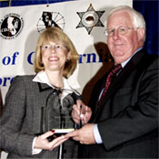 Coordinator Debora McGlynn (left) accepts her award from POST Commission Chairman Jim Fox